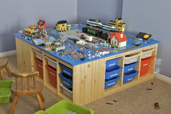 This is the table I built for my kids' LEGO collection for Christmas 2009. The base is made from four slotted organizers from IKEA. The bins (also from IKEA) are made to slide into all the nice slots. The table top is made from a 5' x 5' piece of baltic birch plywood cut to 4' 8". I rounded the corners of the top, routed 1/8" edge, and sanded it using an orbital sander. I then used spray paint (first coat is white primer, then royal blue -- which matched the blue LEGO color exactly, and then a clear coat) bought from Home Depot. The kids love it and so do I since their LEGO stuff is now much more organized and stays in one area of the house (though it looks kinda messy in this pictures because of being in the middle of a few new projects).